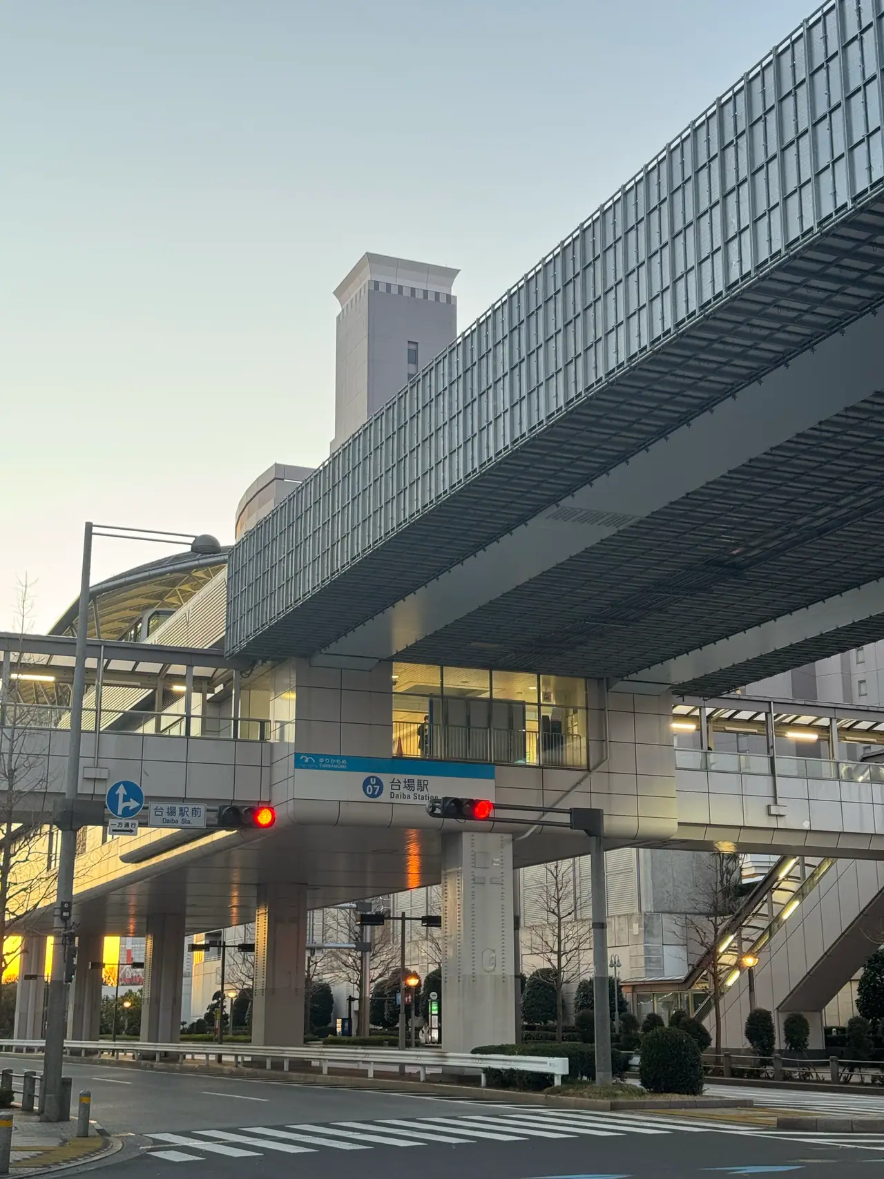 Elevated roadways cross above a station entrance in the last light of the afternoon.