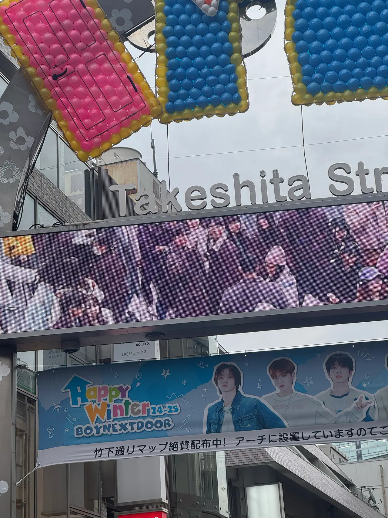 Colourful padded shapes hang from the Takeshita Street arch above a large printed banner.