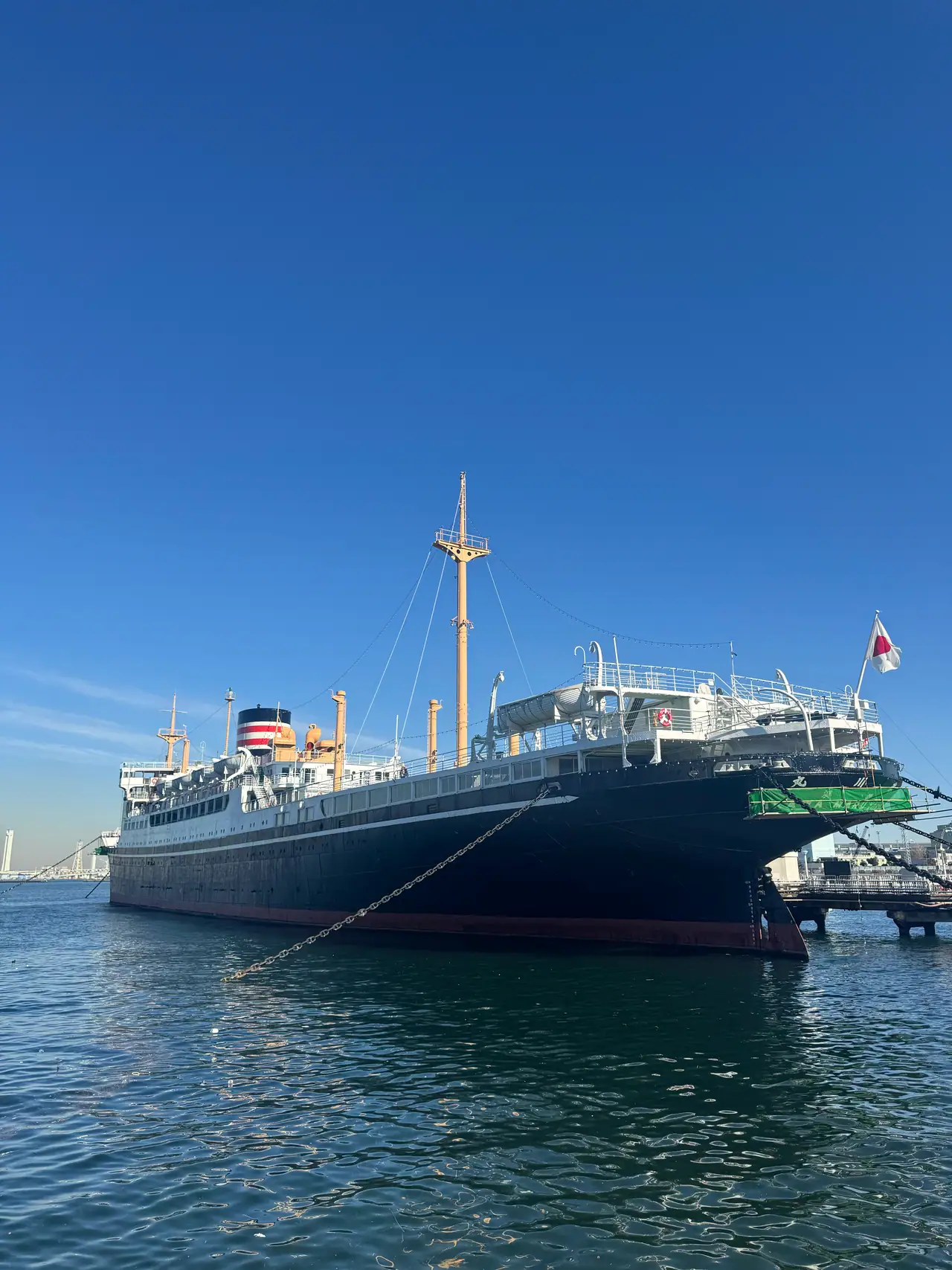 The black and green hull of the Hikawa Maru lies moored along the quay.